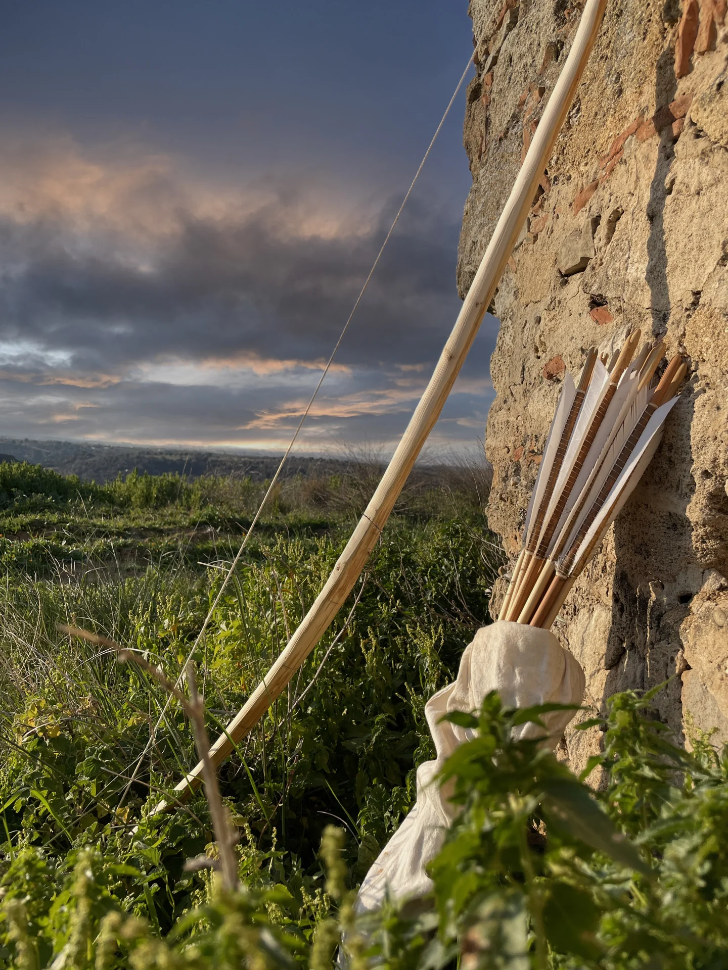Arco e frecce artigianali accanto a un muro in pietra